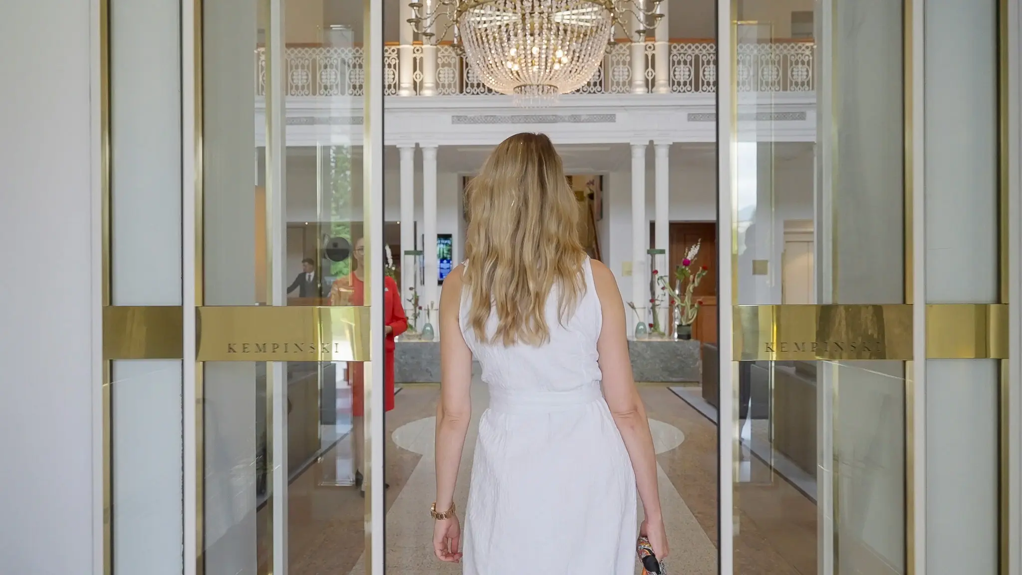 Woman in white dress entering hotel
